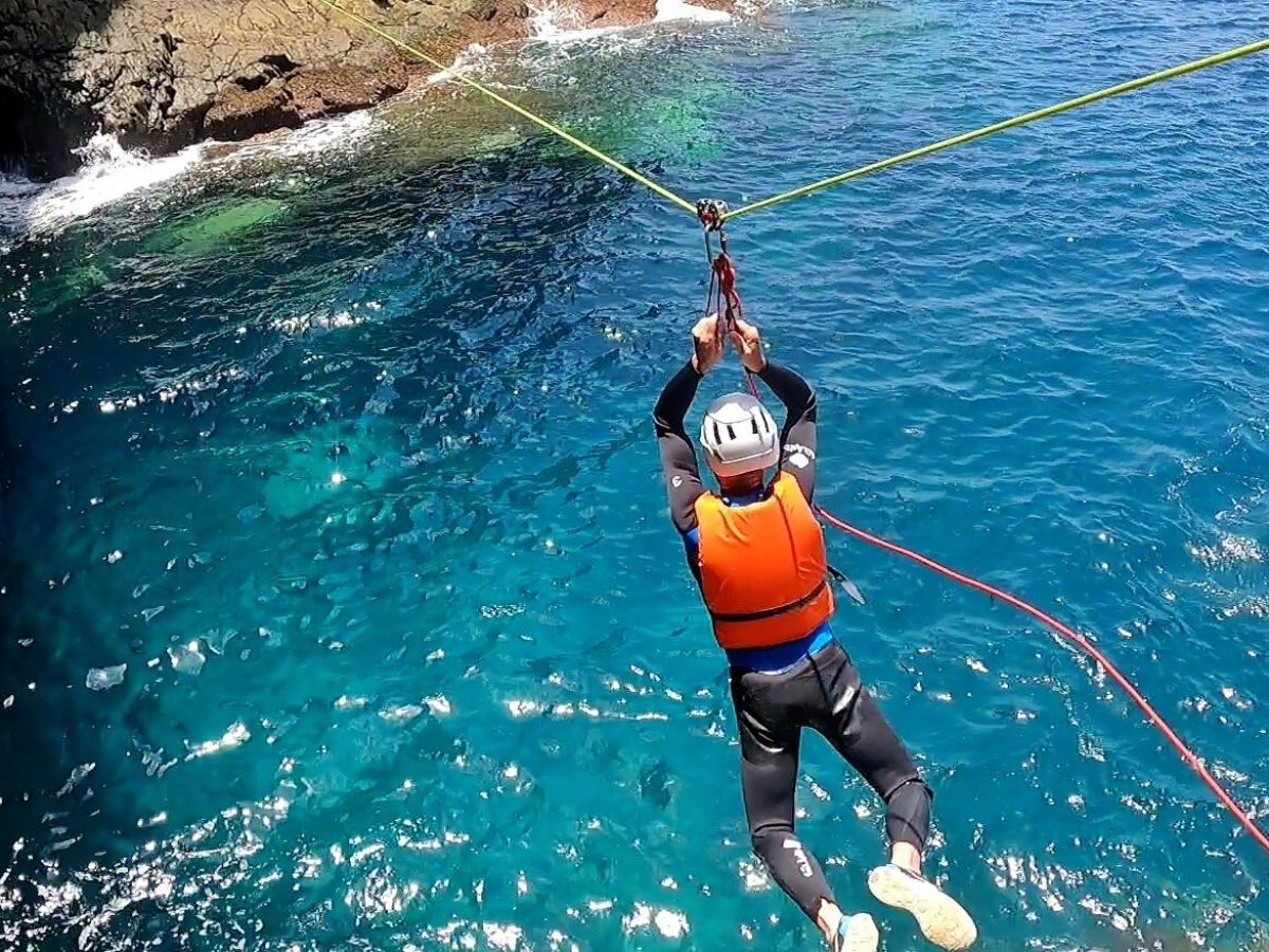 a person ziplinging between rocky cliffs