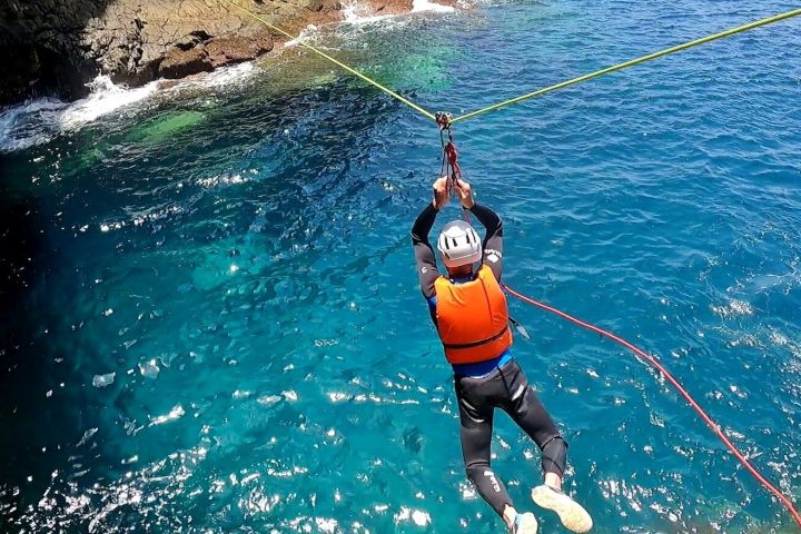 a person ziplinging between rocky cliffs